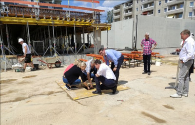 Die Zeitkapsel wird gemeinsam mit Bauherrn, Bauleiterin und Bürgermeister in die Öffnung gelegt