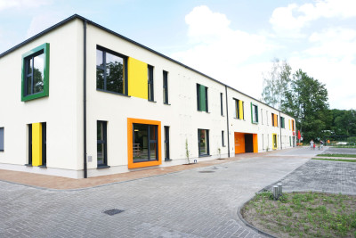 Das Haus steht parallel zum Schönfelder Weg, im hinteren Teil ist eine Bäcker-Filiale eingezogen