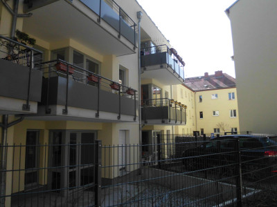 Rückansicht des Hauses mit Balkonen, die zur Stadtmauer und den vielen Bäumen dahinter weisen